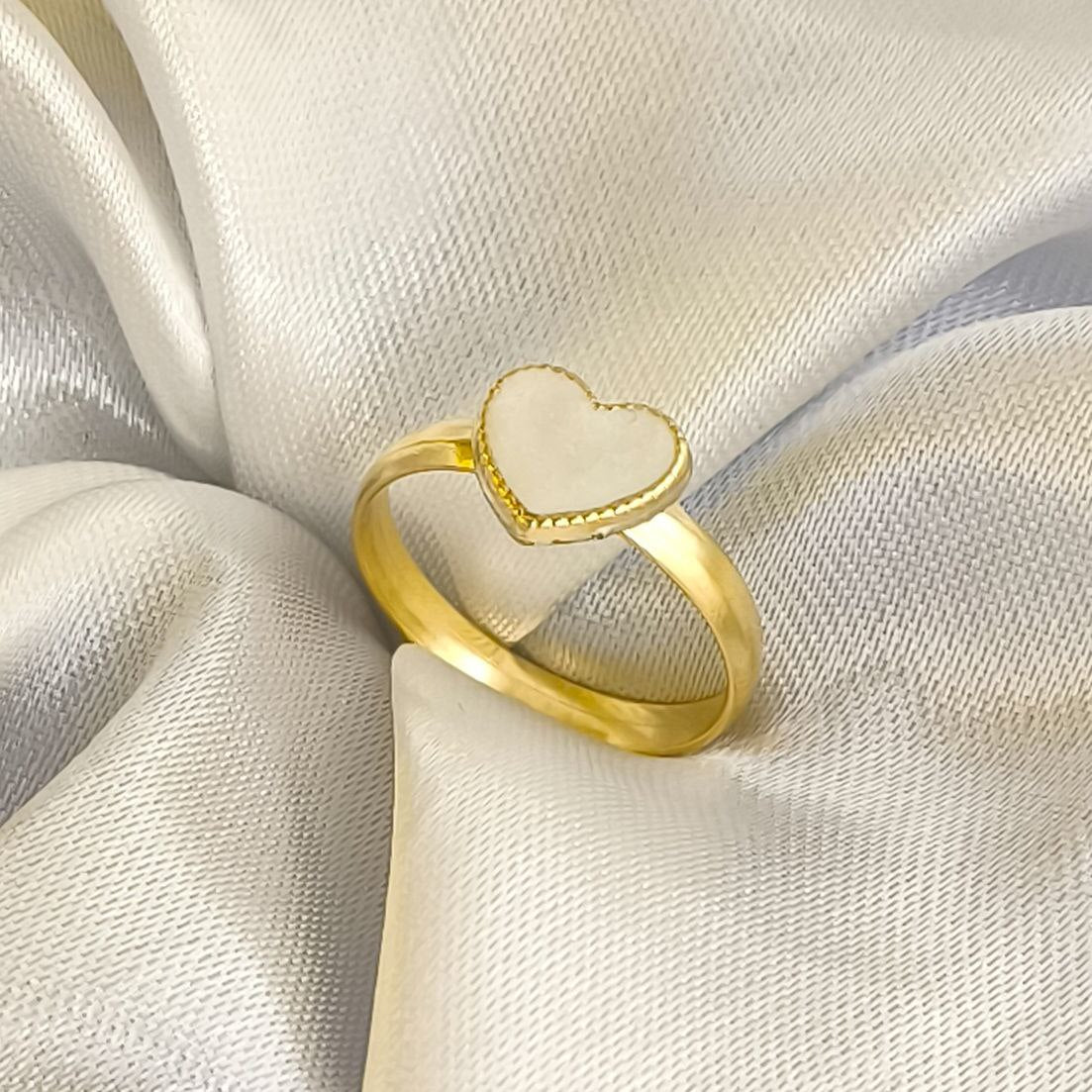Anillo de corazón blanco en oro laminado de 18k sobre fondo de seda.