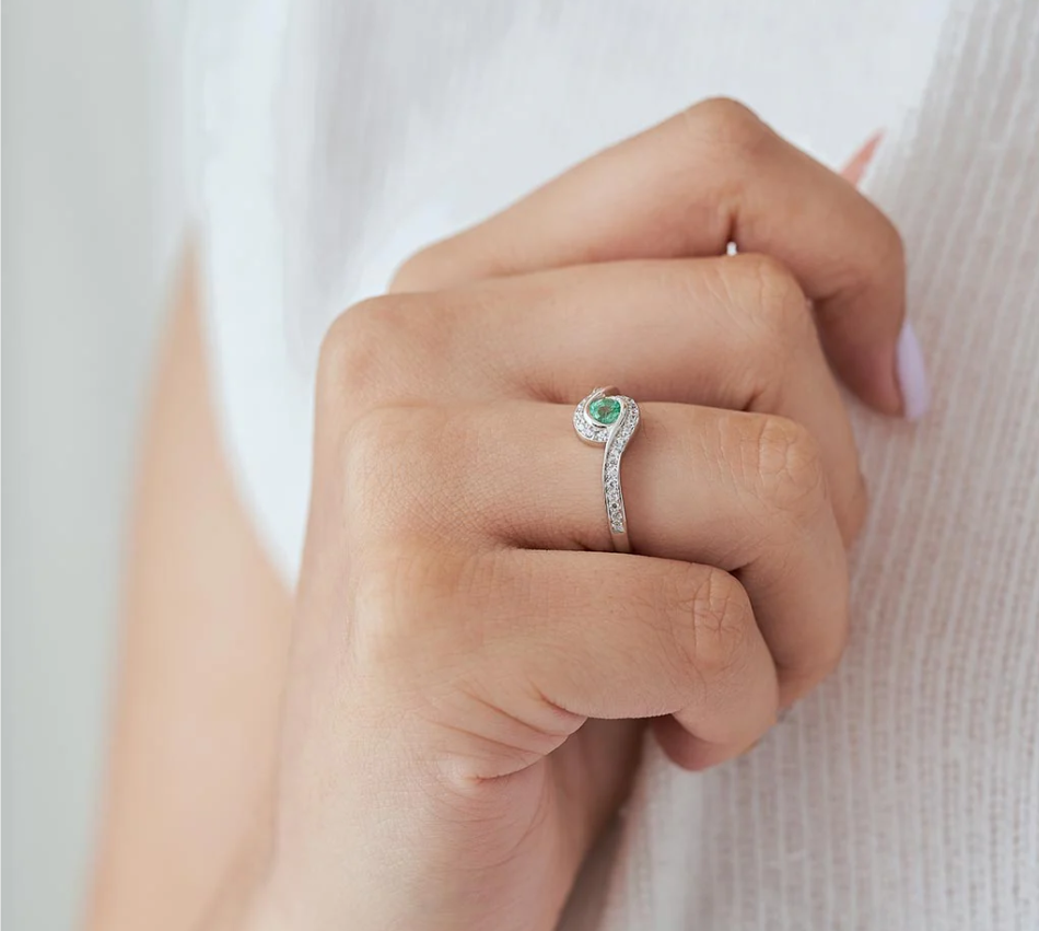 Anillo de compromiso con esmeralda colombiana y diamantes puesto en mano de mujer, joyería artesanal Colombia