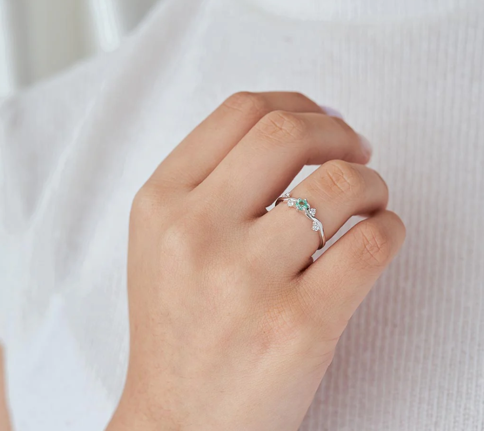 Anillo de compromiso orgánico con esmeralda colombiana y diamantes de laboratorio puesto en mano de mujer, joyería artesanal Colombia