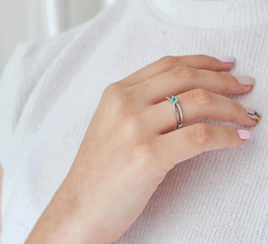 Anillo de compromiso elegante con esmeralda colombiana y diamantes blancos diseño nudos puesto en mano de mujer, hecho a mano Colombia