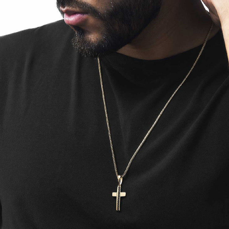 Cruz con piedras negras oro 18k puesta en hombre con camiseta negra - Brillo Encanto
