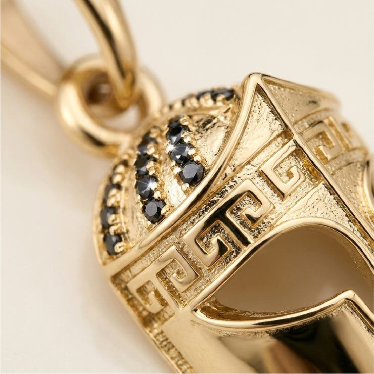 Detalle macro dije casco guerrero oro 18k con zirconias negras y grabado greca espartana - acabado premium Brillo Encanto