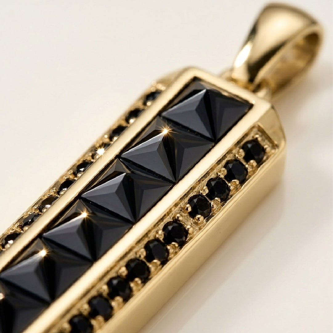 Detalle macro piedras negras cuadradas y redondas engastadas en dije barra oro 18k