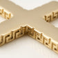 Detalle macro textura greca dije cruz oro laminado 18k - grabado artesanal bordes dorados Brillo Encanto