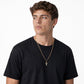 Hombre joven con dije cruz oro 18k sobre cadena dorada y camiseta negra - joyería de lujo Colombia
