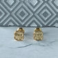 Detalle de los aretes topitos dorados con diseño de trébol