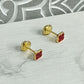 Par de aretes para bebé con forma de trébol rojo en oro laminado 18K, con rosca de seguridad, sobre fondo blanco.