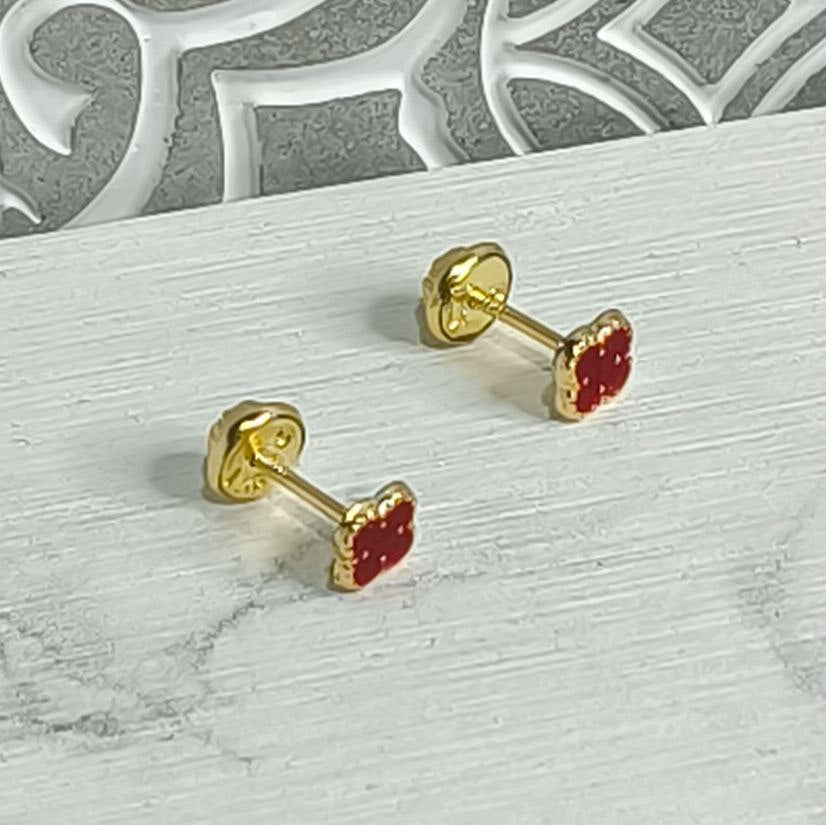 Par de aretes para bebé con forma de trébol rojo en oro laminado 18K, con rosca de seguridad, sobre fondo blanco.