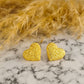 Detalle de textura en aretes corazón martillados - Joyería hipoalergénica premium