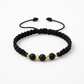 Pulsera unisex de hilo negro tejido con cuentas negras y balines de oro 18K, con cierre ajustable.